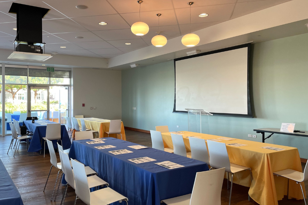 Projector screen and 6 feet long tables and seats in Terrace Room on the morning of the Neurobehavioral Genetics Retreat hosted on May 12, 2022 at the Annenberg Community Beach House