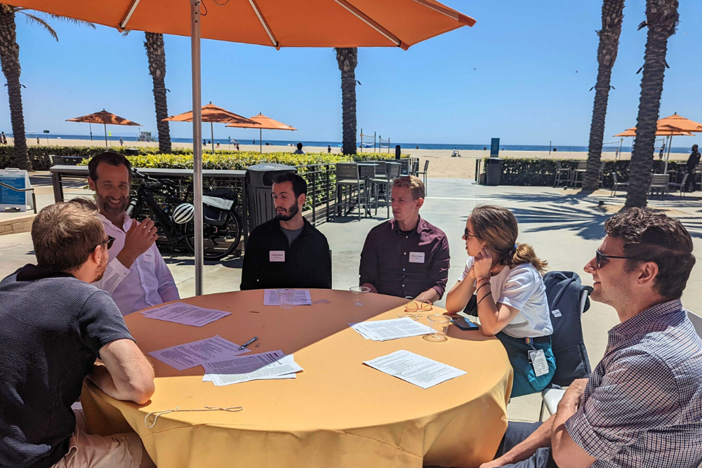 Attendees (faculty, postdoctoral scholars, graduate students, and staff) seated at tables outdoors, participating in a lunch discussion on Responsible Conduct of Research at the Neurobehavioral Genetics Retreat hosted on May 12, 2022 at the Annenberg Community Beach House.